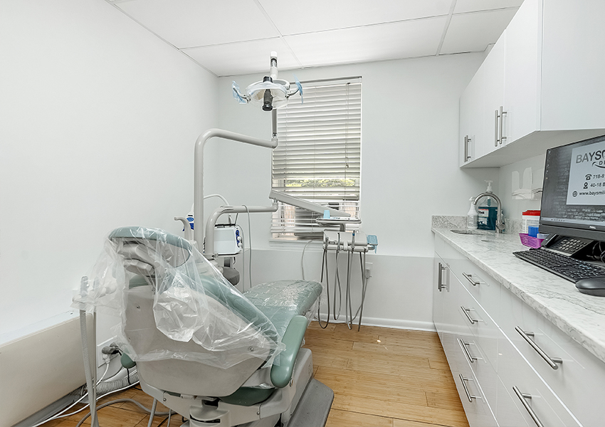 A dental treatment room with a chair, desk, and equipment.