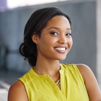 A woman in a yellow top smiles at the camera.