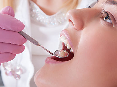 Woman receiving dental care, with a dentist using a drill on her teeth.