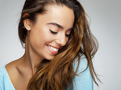 A woman with long hair, smiling gently, against a plain background.